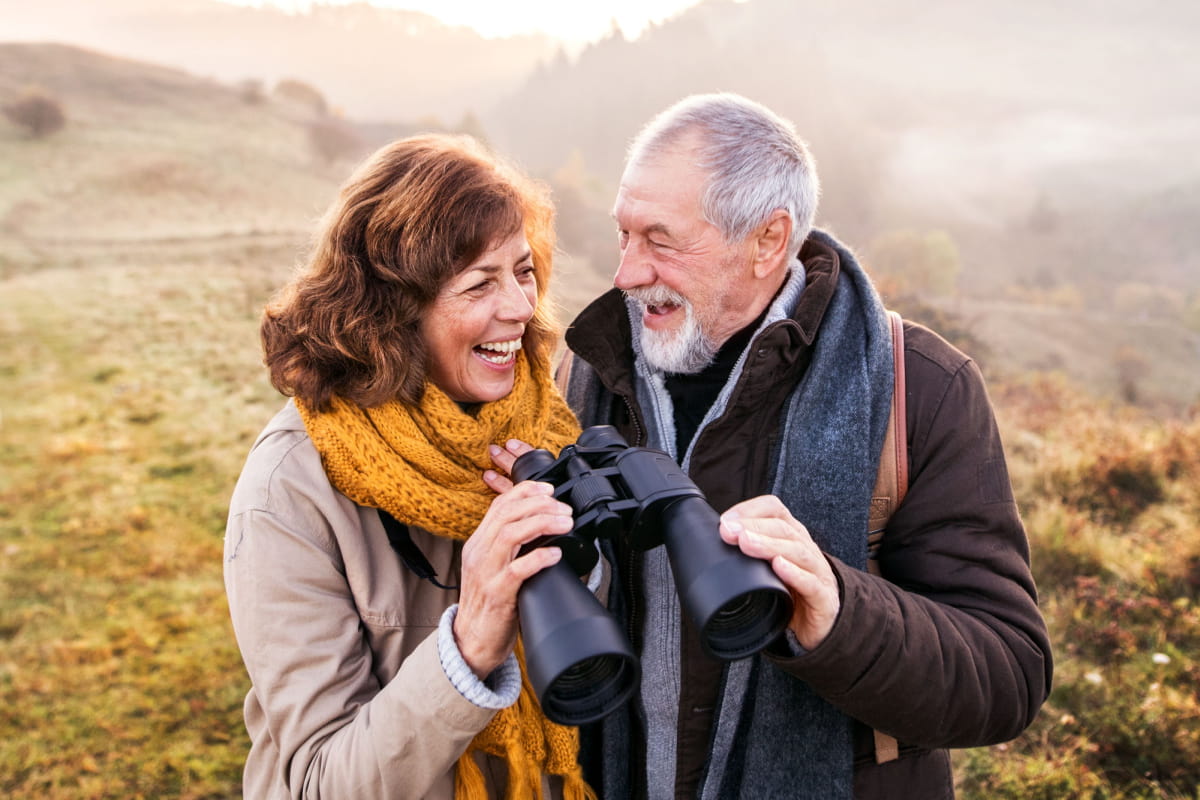 senior couple hiking and using binoculars