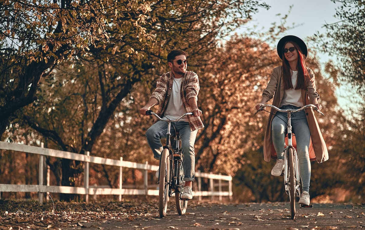 a couple riding bikes on path in autumn
