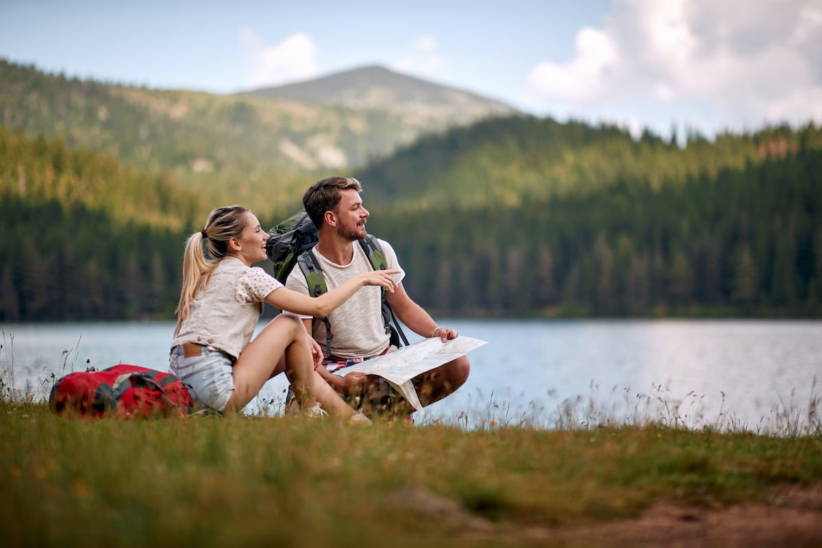 young couple having a picnic and looking at mountains in the distance