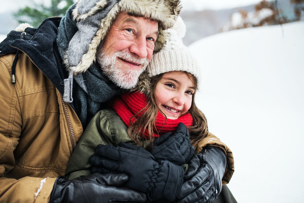 senior man and his granddaughter playing in the snow