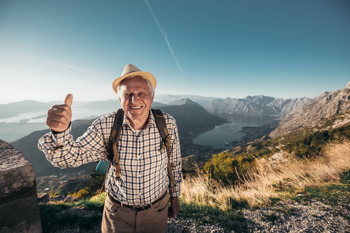happy senior man hiking and giving a thumbs up