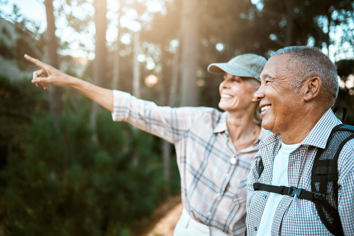 two middle aged people hiking during the summer and pointing at things in the distance