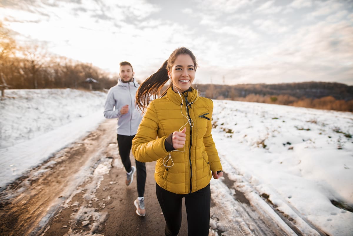 young couple running outside in winter
