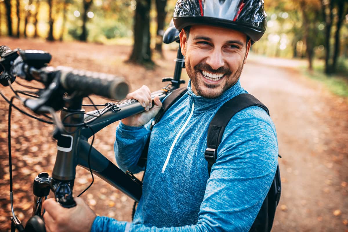 young man mountain biking and carrying his bike