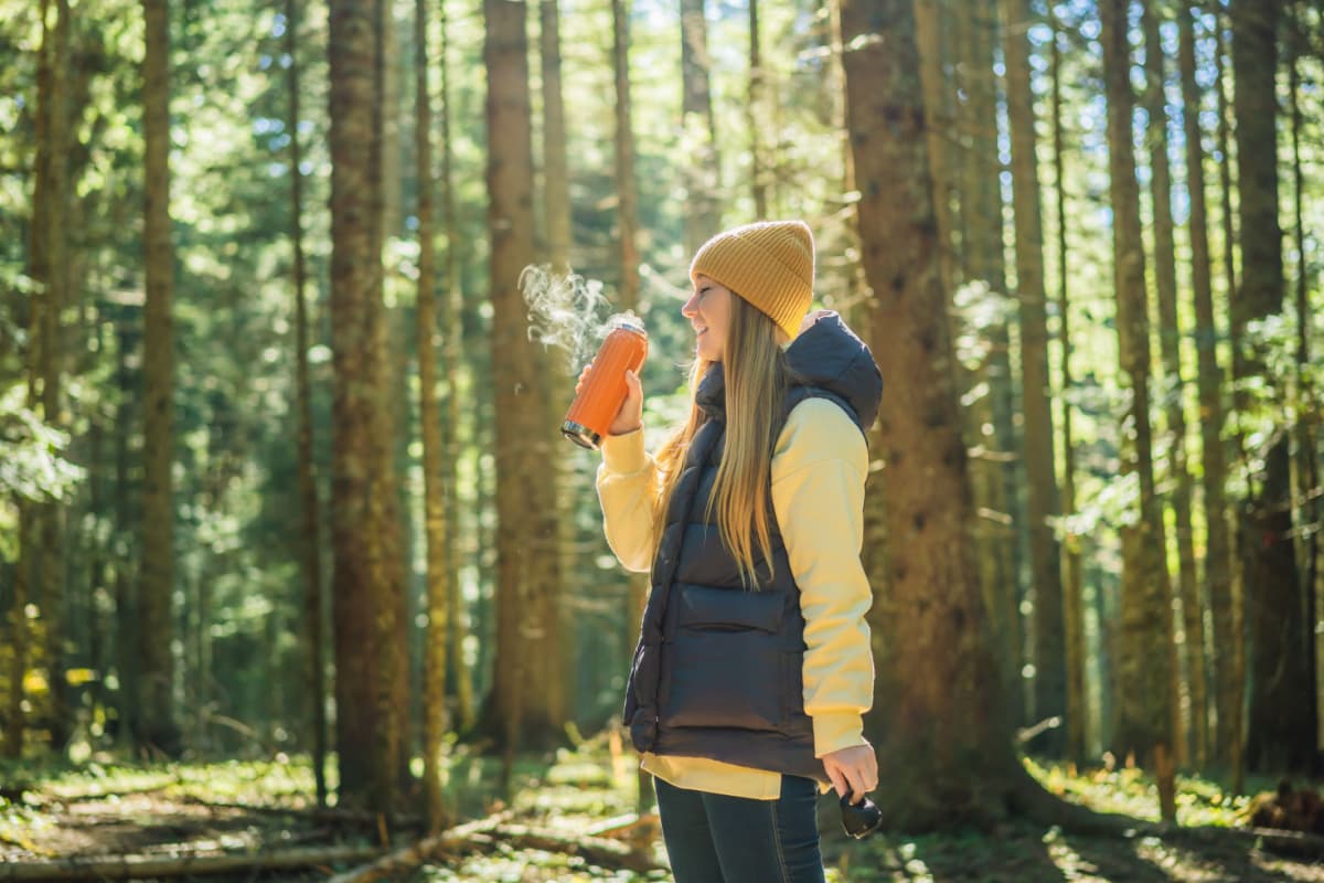 woman camping and drinking coffee in the forest