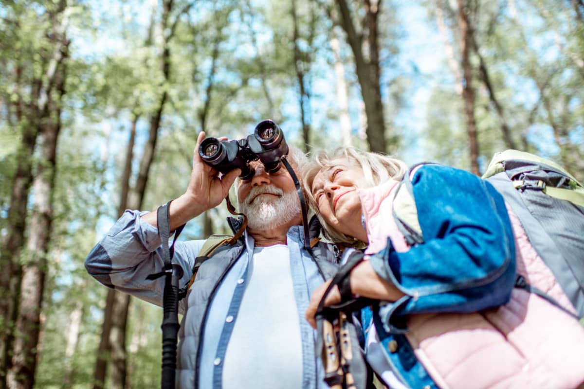 mature hikers using binoculars